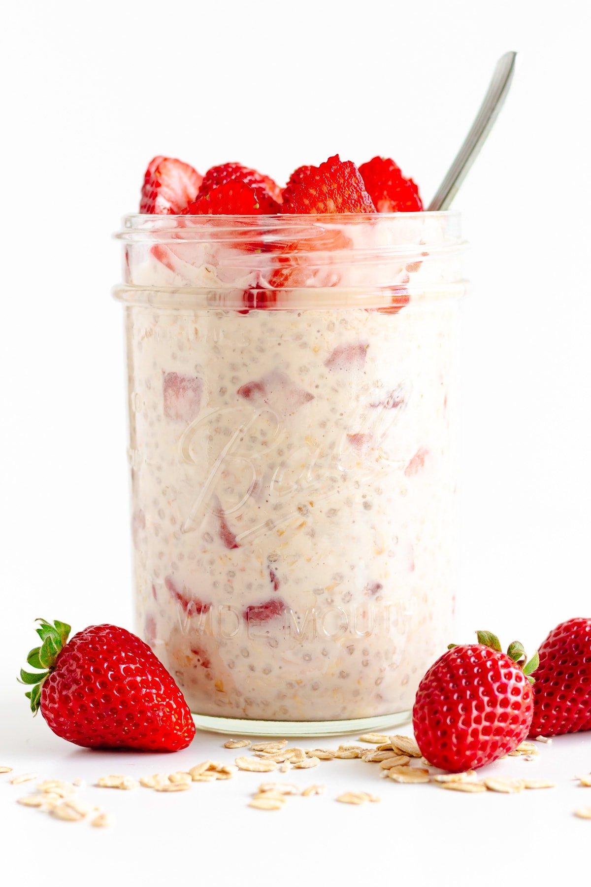 Mason jar filled with strawberry overnight oats and topping with fresh strawberry slices.