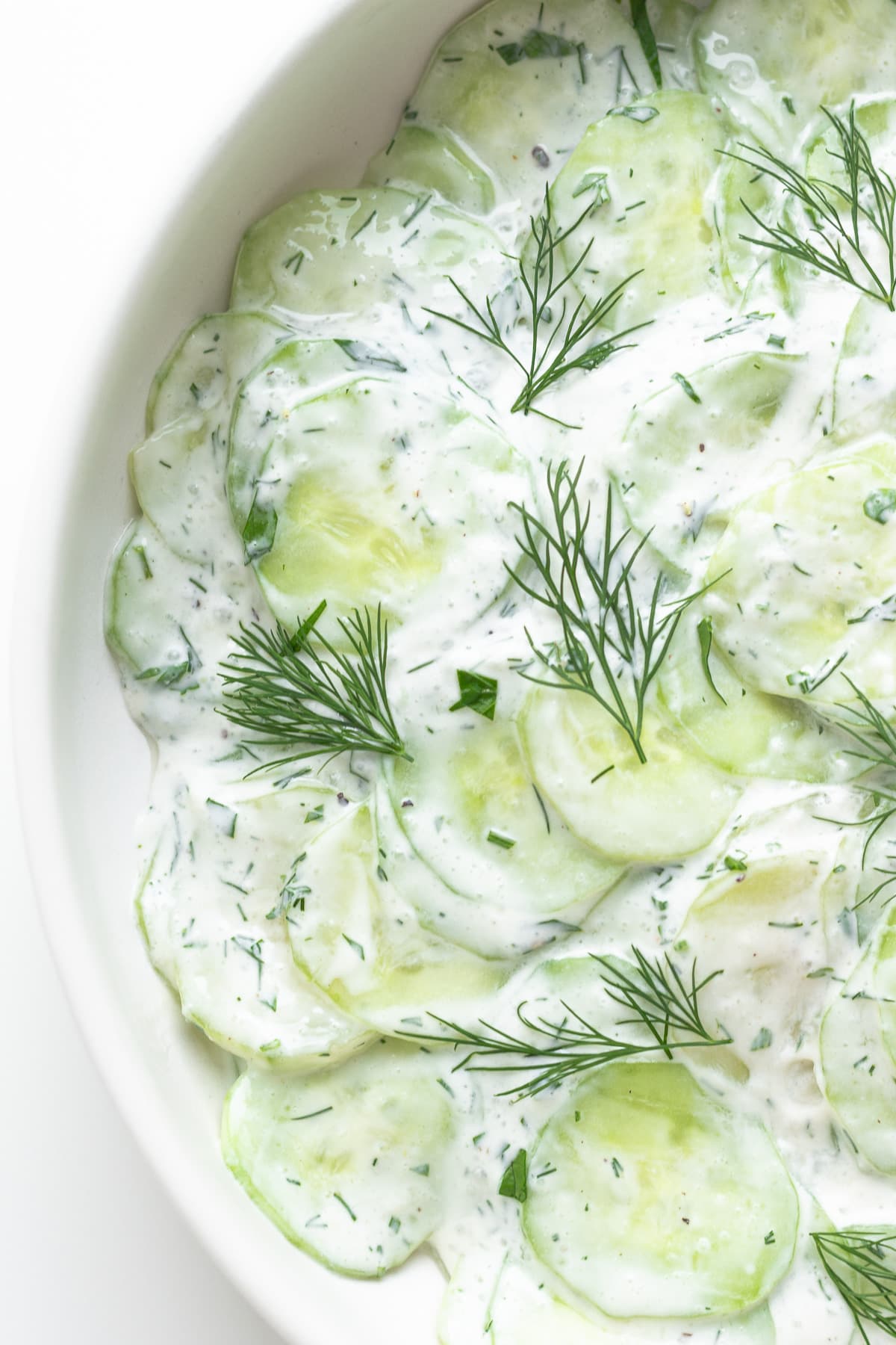 Closeup of Gurkensalat (German cucumber salad) in a white bowl.