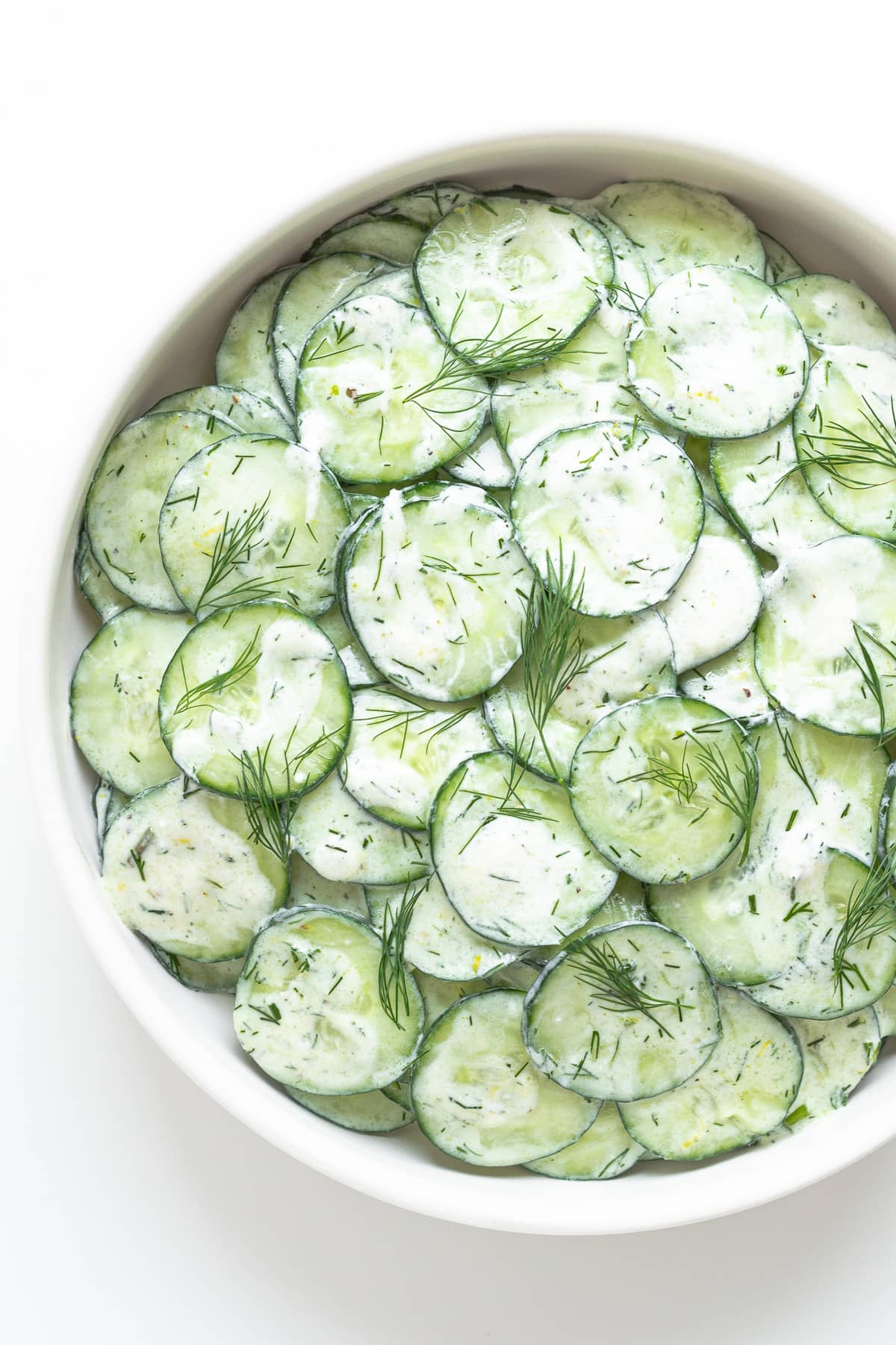 Cucumber yogurt salad in a white bowl.