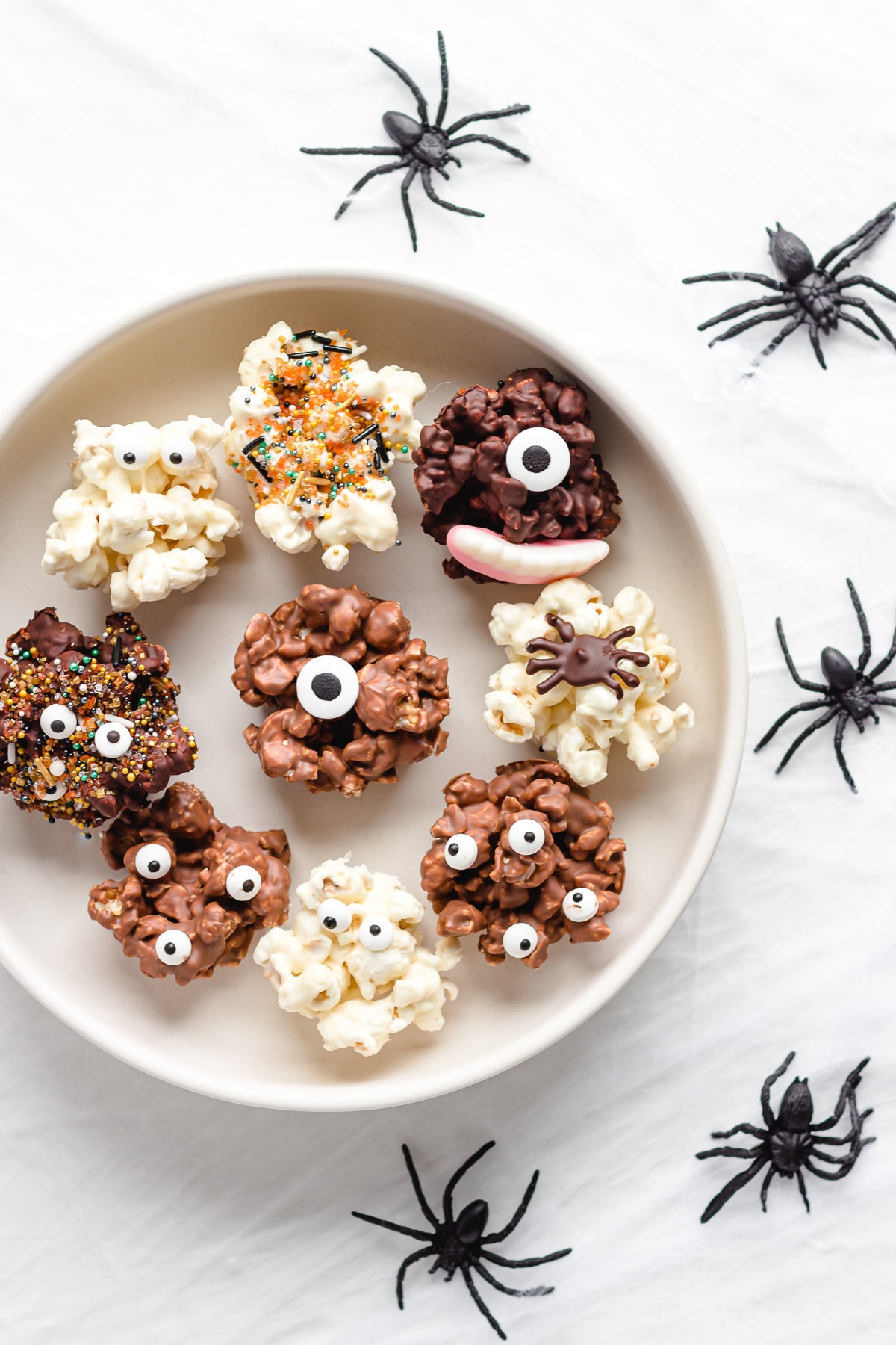 Serving platter of chocolate Halloween popcorn balls with fake spiders crawling next to it.
