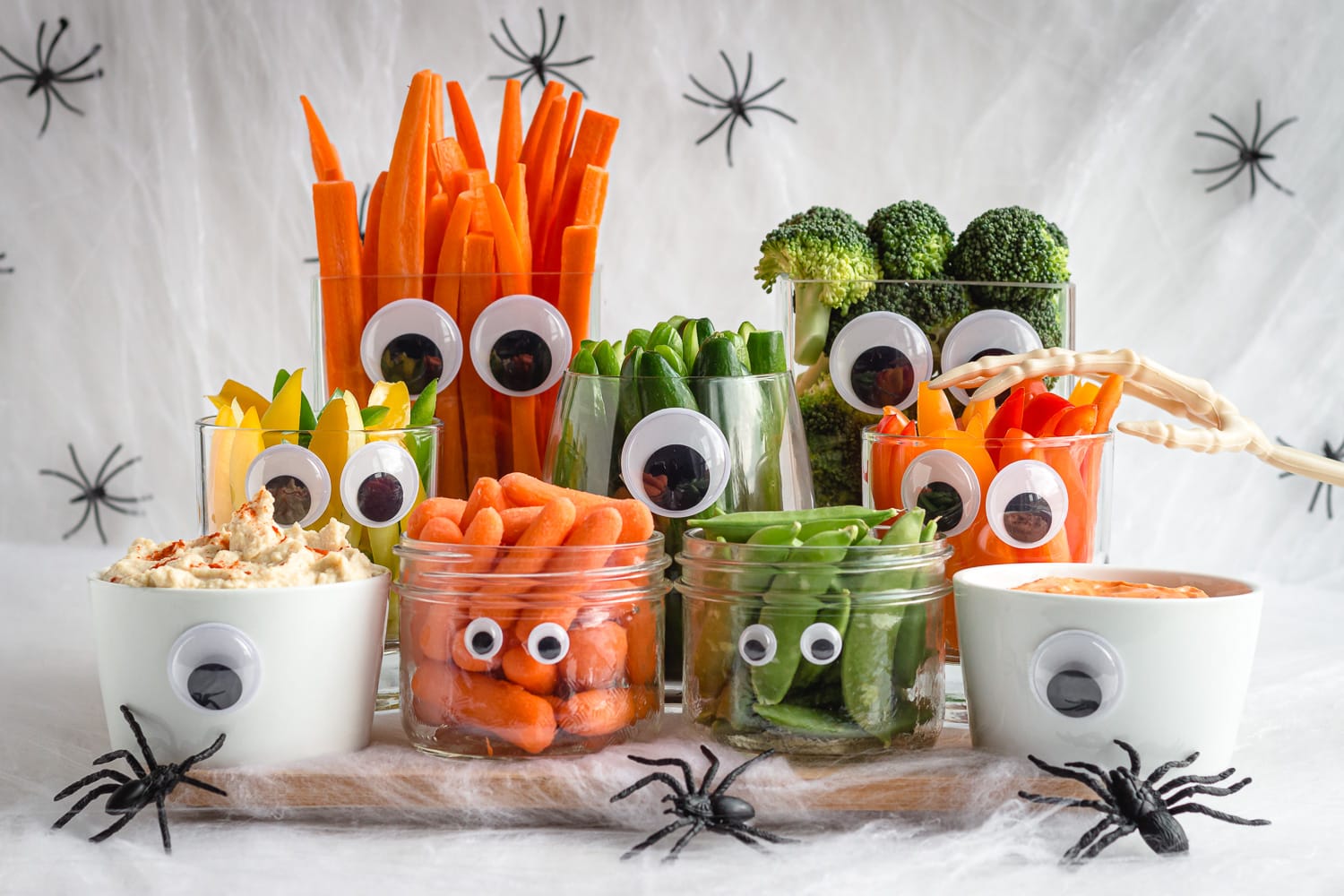 Halloween themed vegetables and dip surrounded by fake cobwebs and spiders.