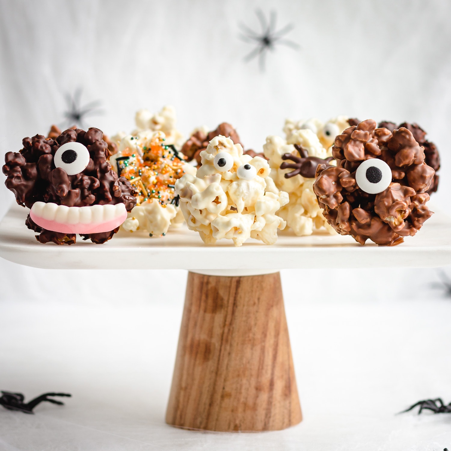 Cake stand with a variety of different Halloween popcorn balls on it.