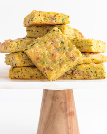 Pile of zucchini slice on a marble and wood cake stand.