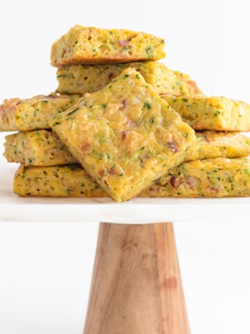 Pile of zucchini slice on a marble and wood cake stand.