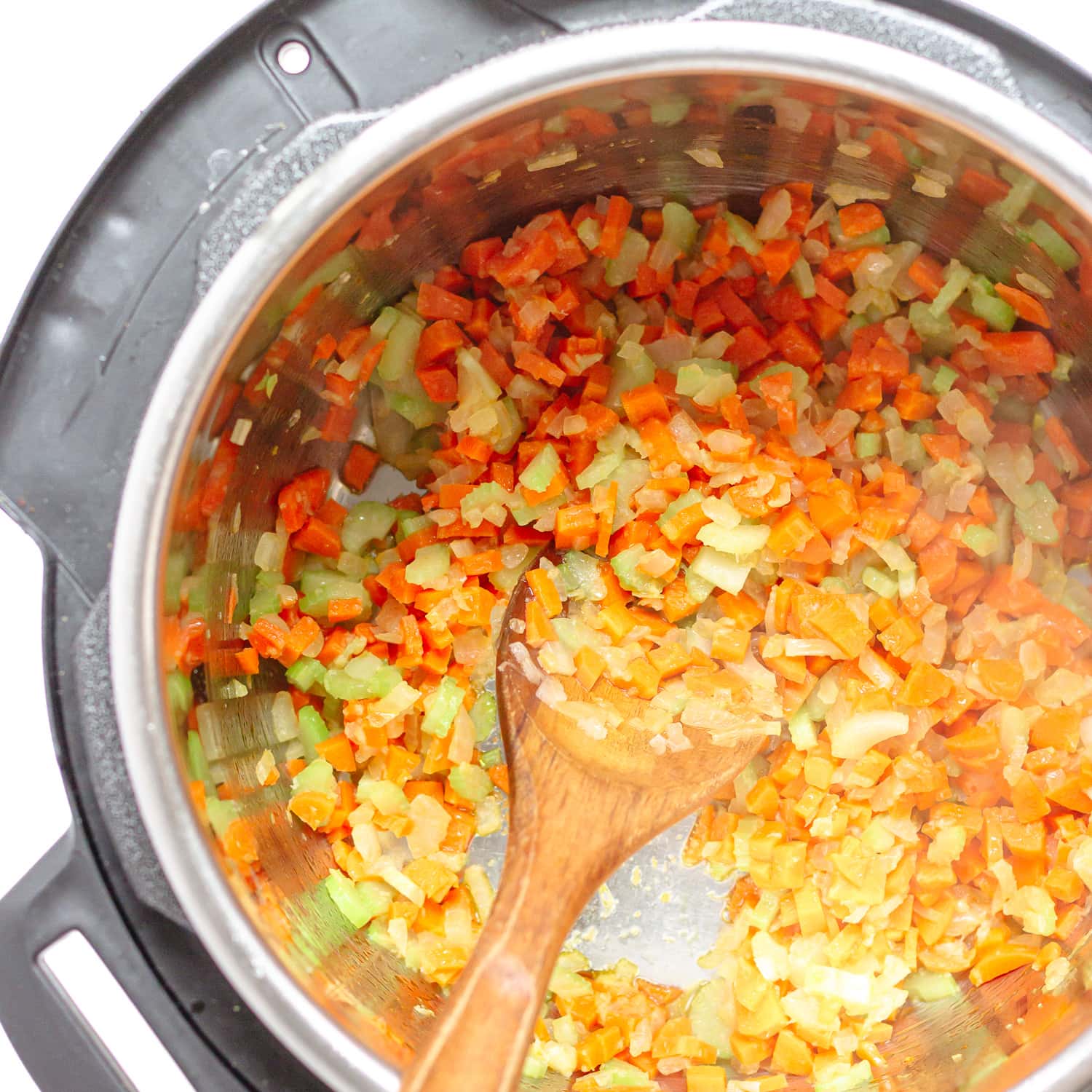 Chopped onions, celery, carrots and garlic being sautéed in an Instant Pot.