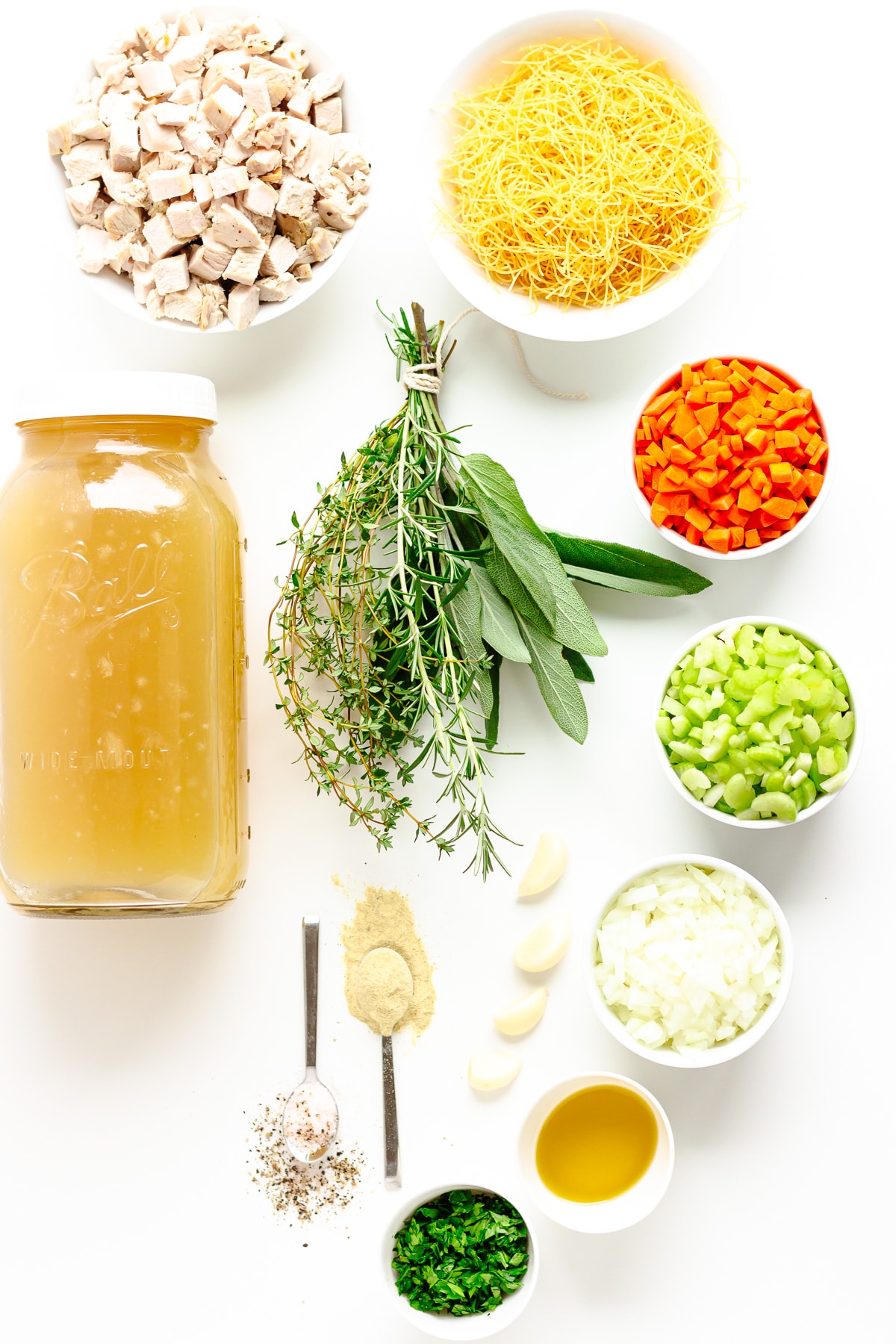 Flat lay of ingredients needed to make turkey soup on a white background.