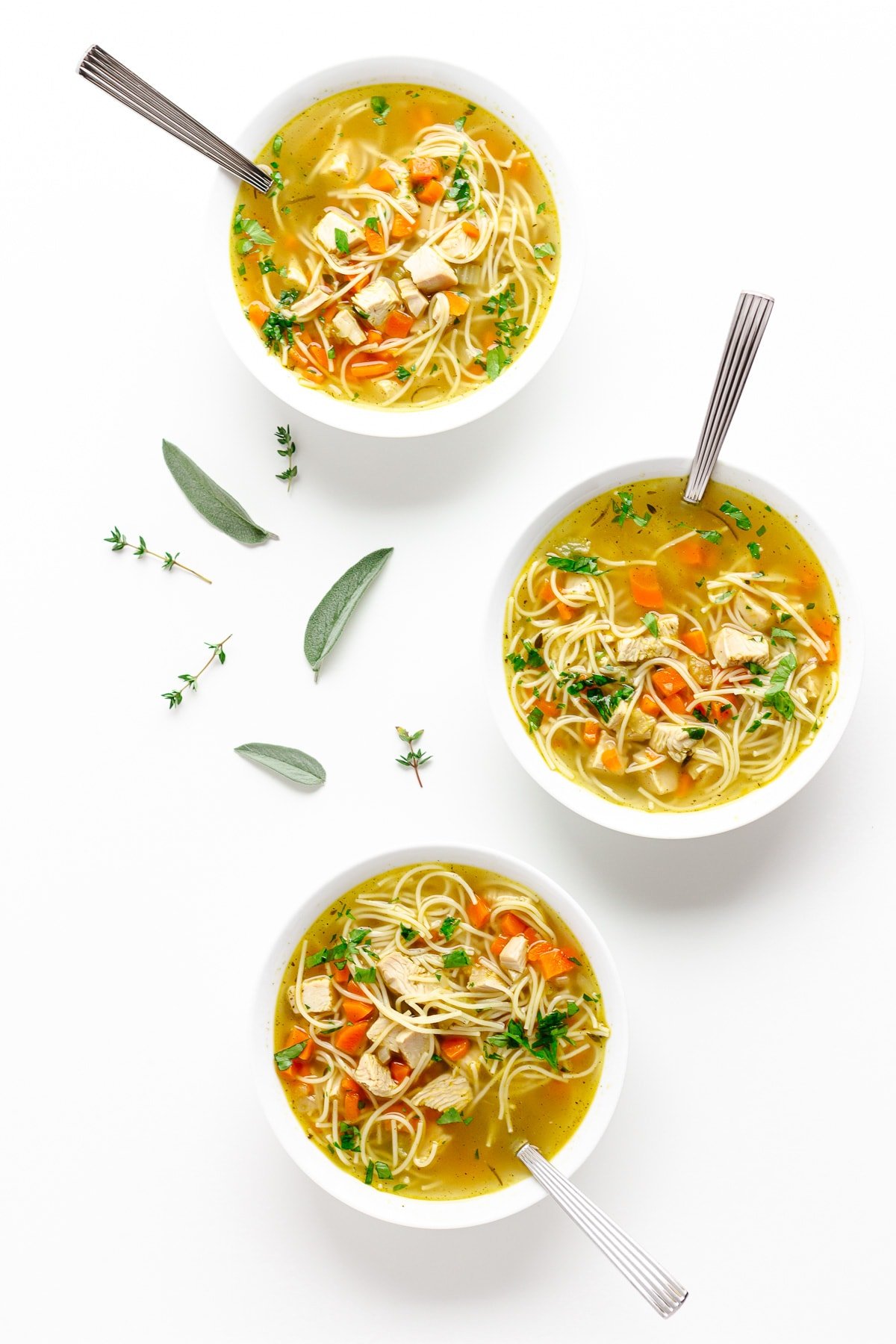 Three bowls of turkey soup on a white background.