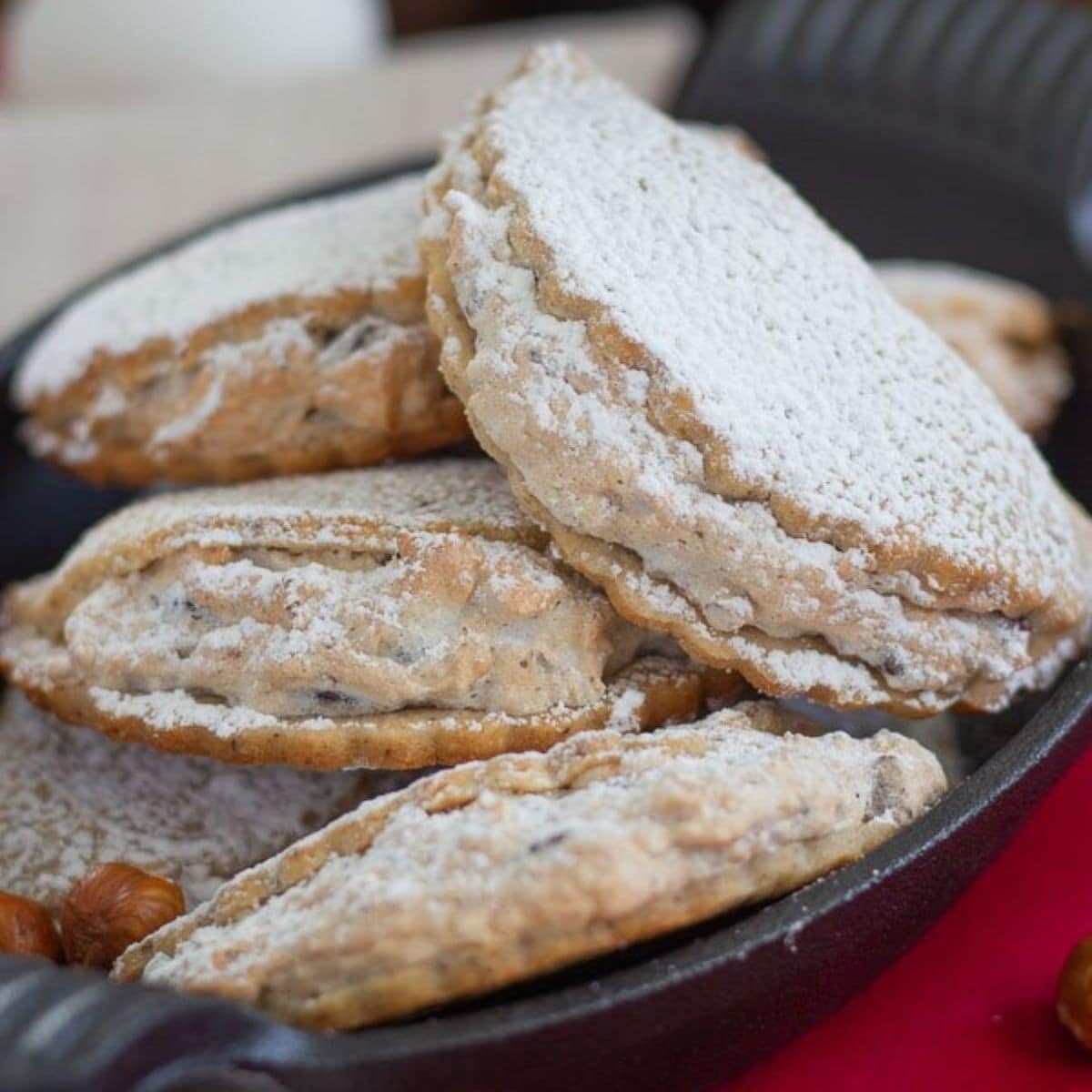 Pile of Haselnusstaschen (German Hazelnut Meringue Cookies) in a black dish.