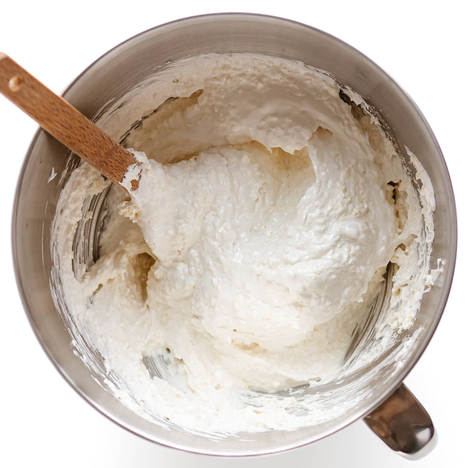 Shredded coconut being folded into meringue mixture.