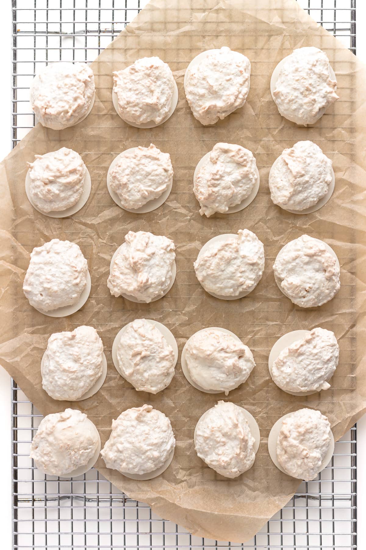 Kokosmakronen (German Coconut Macaroons) on top of a crinkled piece of brown parchment paper on a cooling rack.