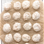 Kokosmakronen (German Coconut Macaroons) on a piece of brown crumpled parchment paper set on top of a wire cooling rack.