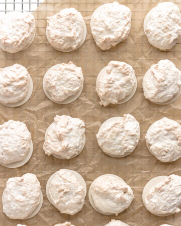 Kokosmakronen (German Coconut Macaroons) on a piece of brown crumpled parchment paper set on top of a wire cooling rack.