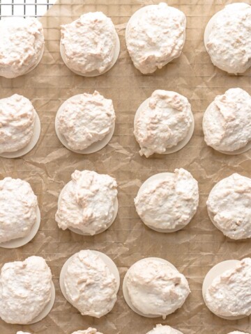 Kokosmakronen (German Coconut Macaroons) on a piece of brown crumpled parchment paper set on top of a wire cooling rack.