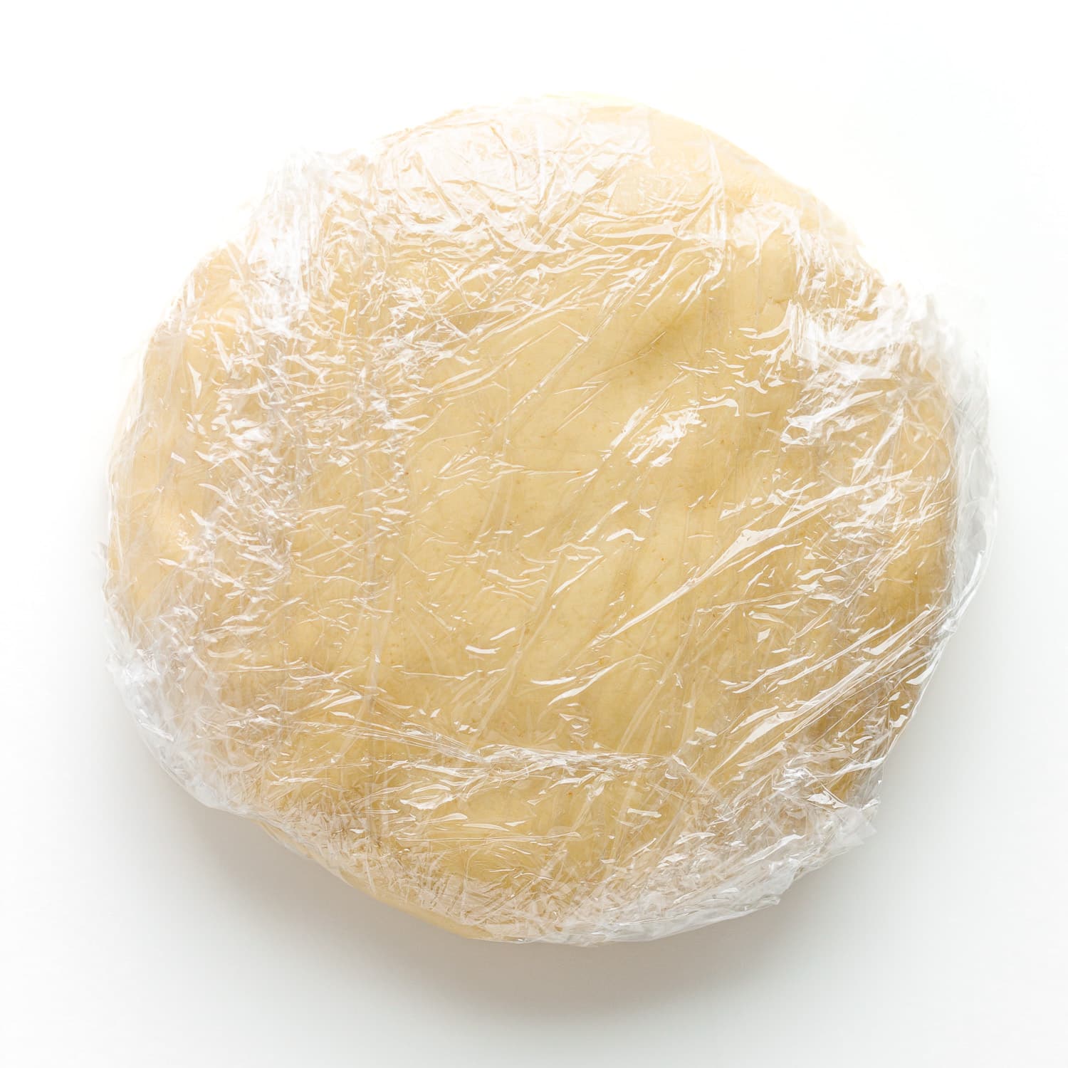 Disc shaped cookie dough wrapped in plastic wrap.