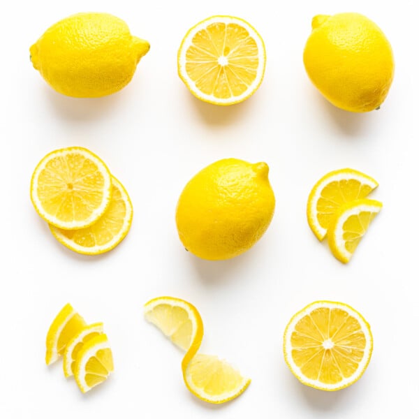 Flat lay of lemons cut in different ways on a white background.