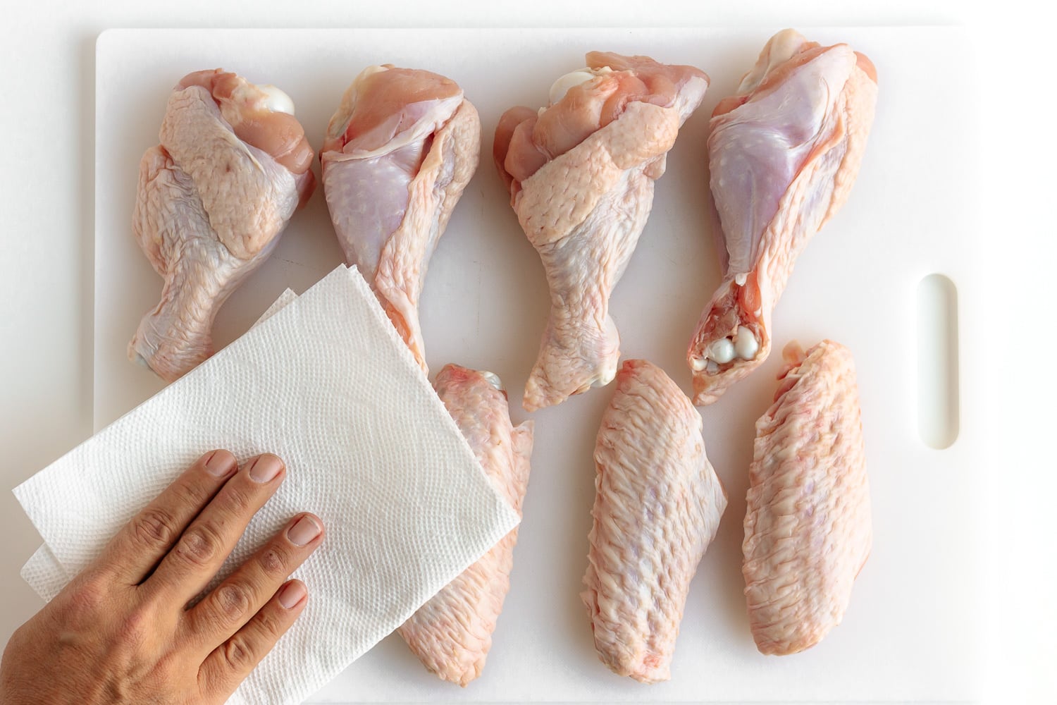 Split turkey wings being dried with a paper towel.