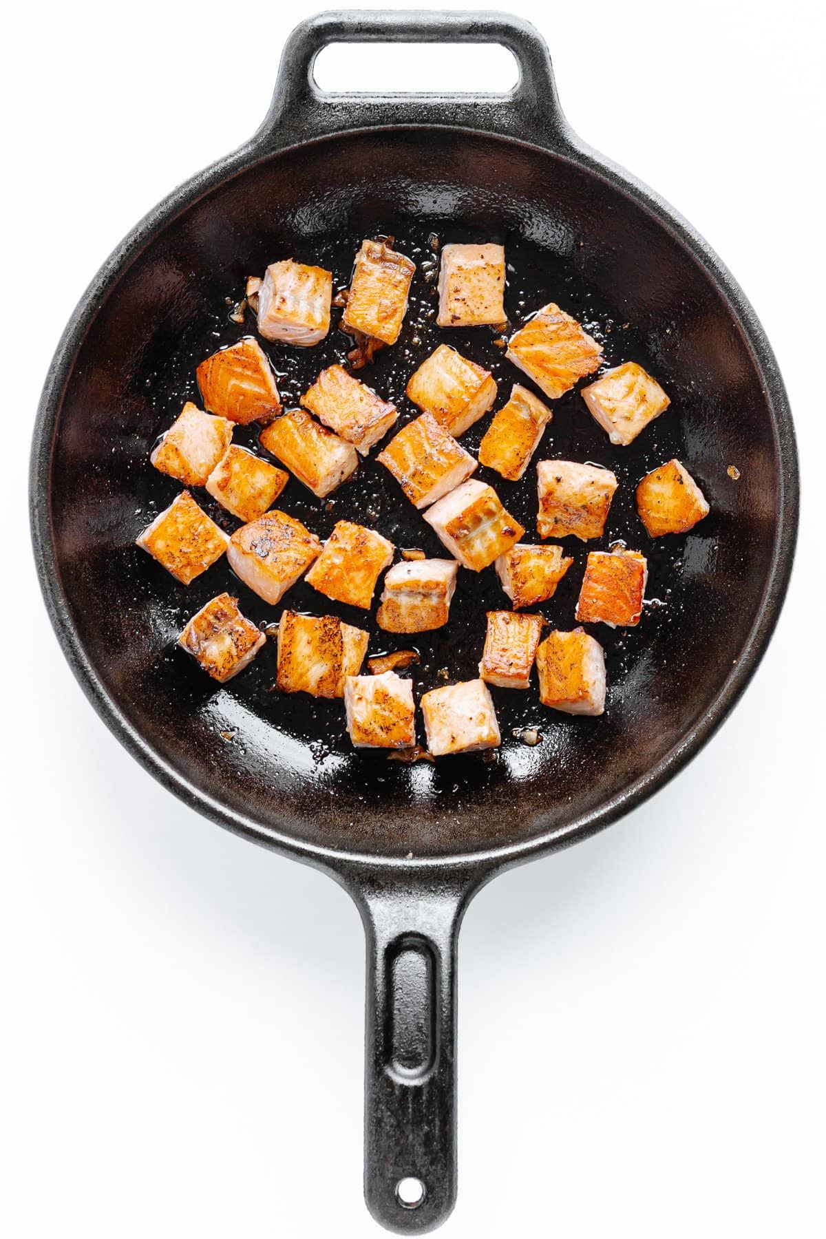 Pan seared cubes of salmon in a cast iron skillet.