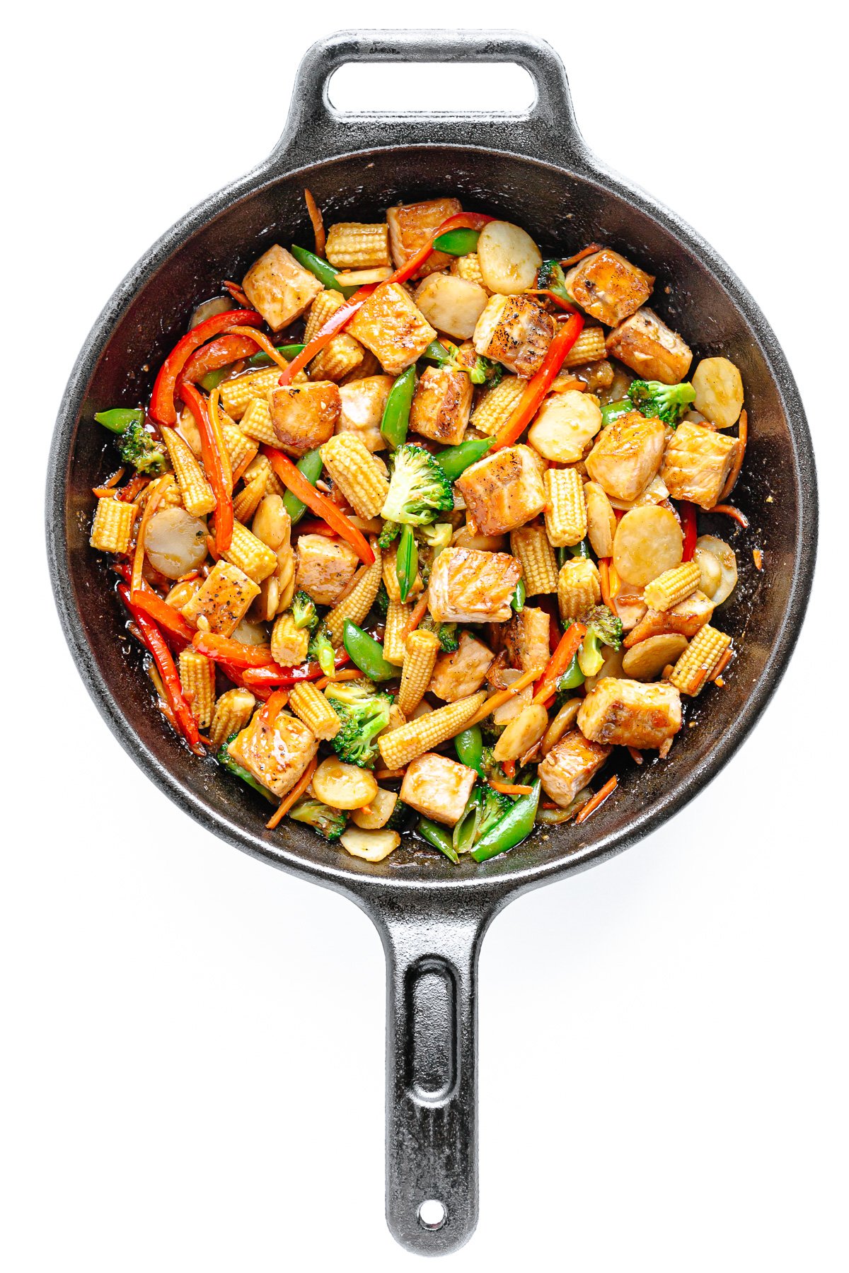 Stir fry in a cast iron skillet on a white background.