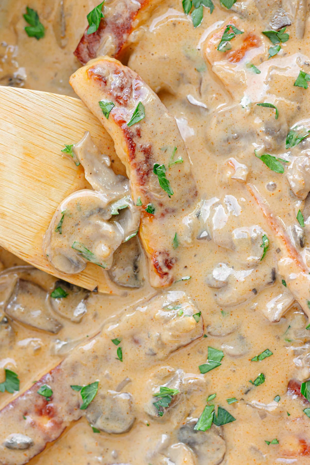 Closeup of Halloumi Mushroom Stroganoff being stirred with a wooden spoon.