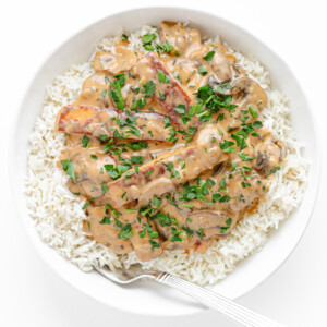 White plate of Halloumi Stroganoff served over rice.