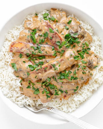 White plate of Halloumi Stroganoff served over rice.