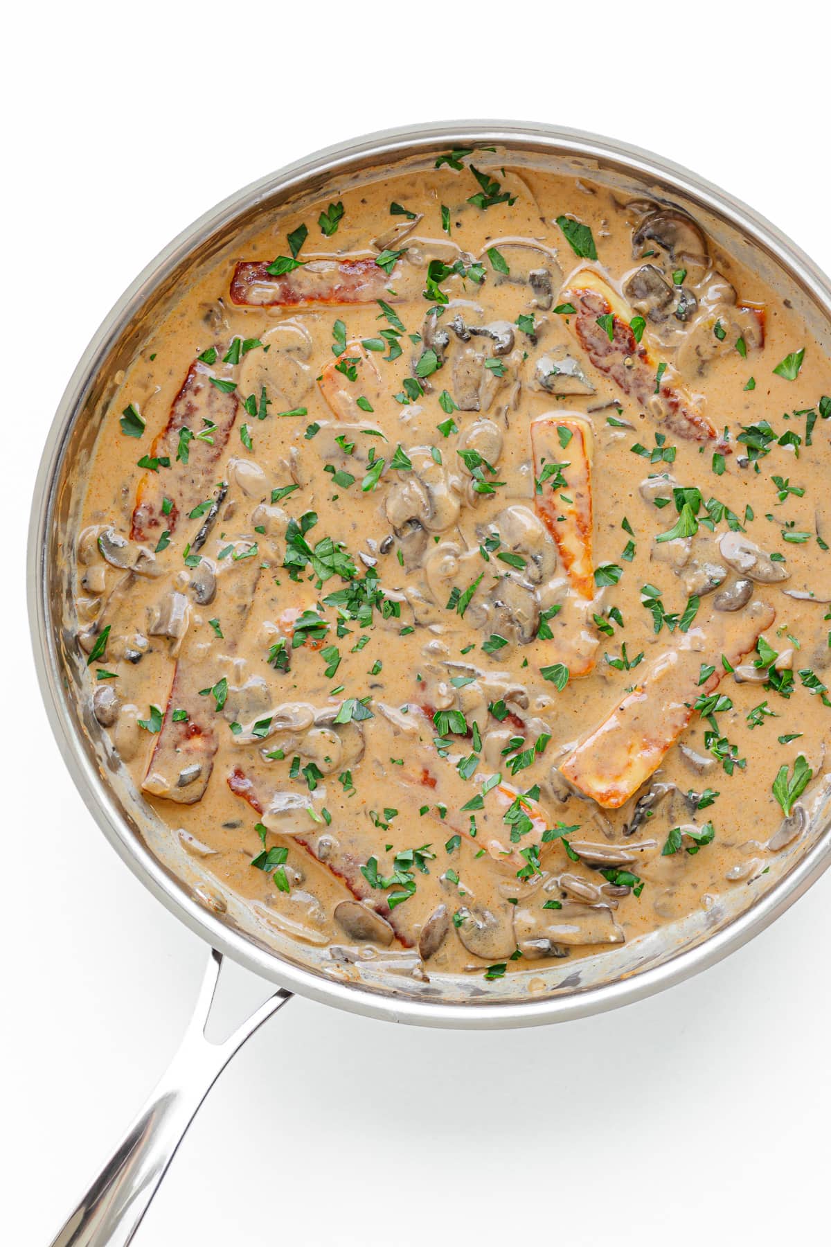 Halloumi Stroganoff in a stainless steel skillet on a white background.