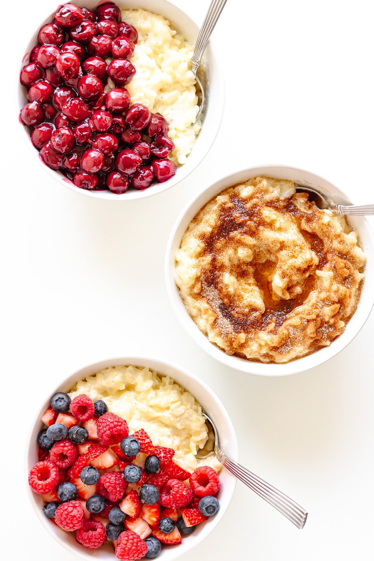 Three bowls of Milchreis (German Milk Rice Pudding) with different toppings.