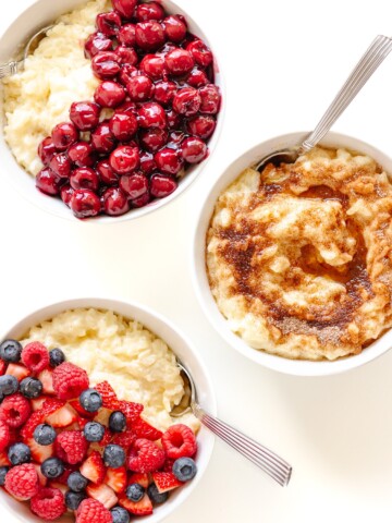 Three bowls of Milchreis (German Rice Pudding) with different toppings displayed on a white background.