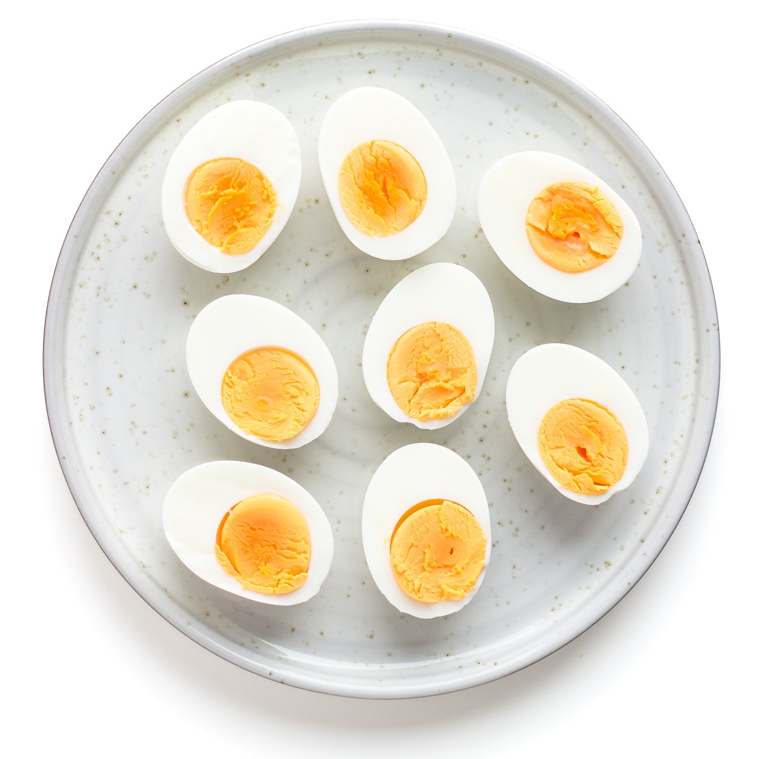 Hard boiled eggs that have been sliced in half arranged on a plate.