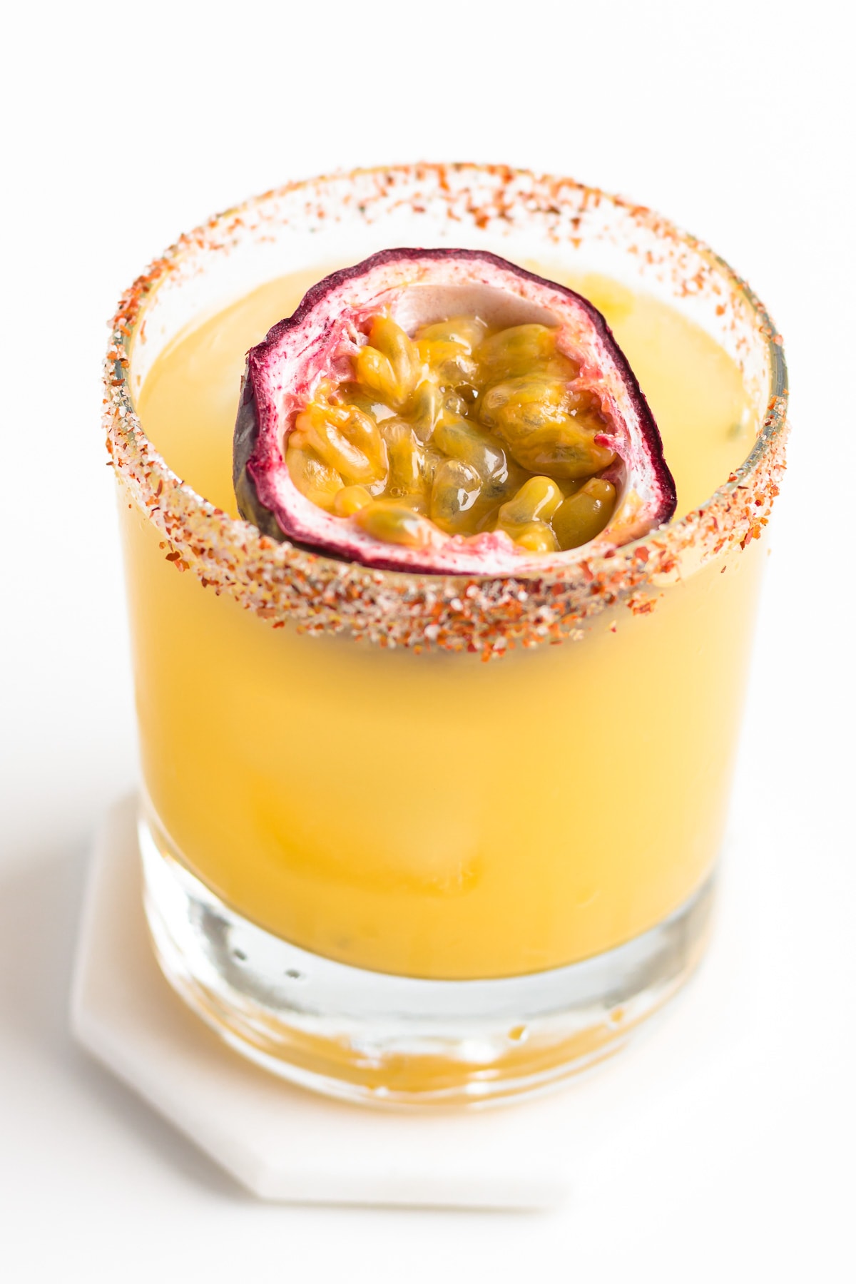 A passion fruit margarita with half a passion fruit floating on top.