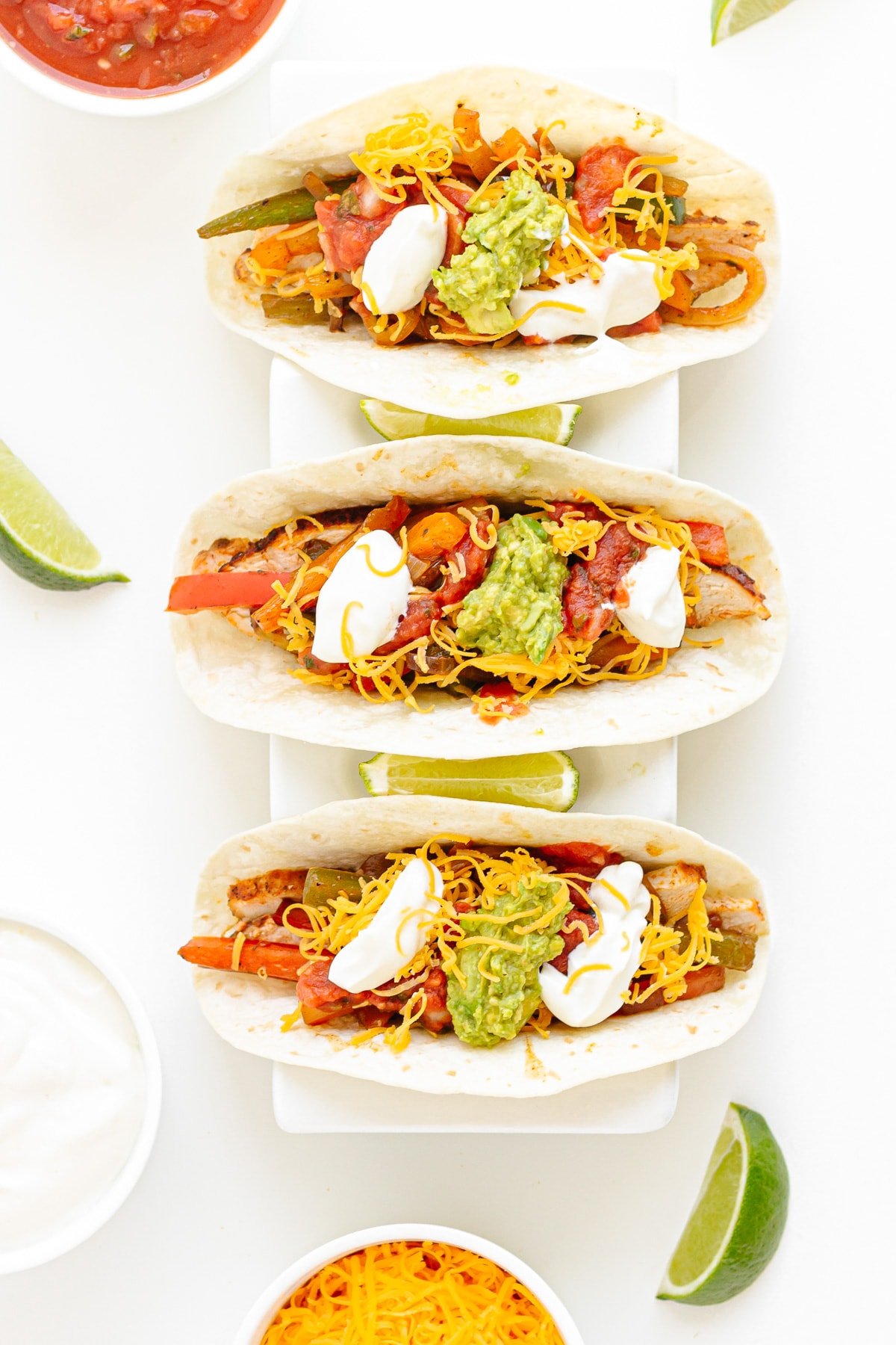 Overhead photo of three chicken fajita tacos in a white taco holder.