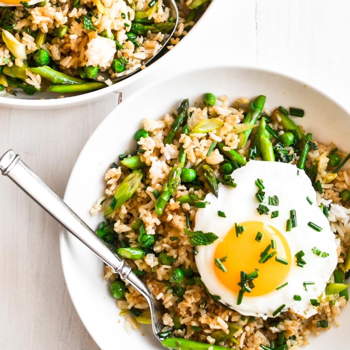 Bowl of asparagus fried rice with a sunny side up fried egg on top.