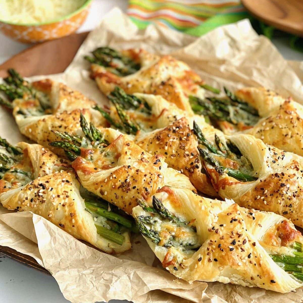 Asparagus puff pastry bundles on a sheet of parchment paper.