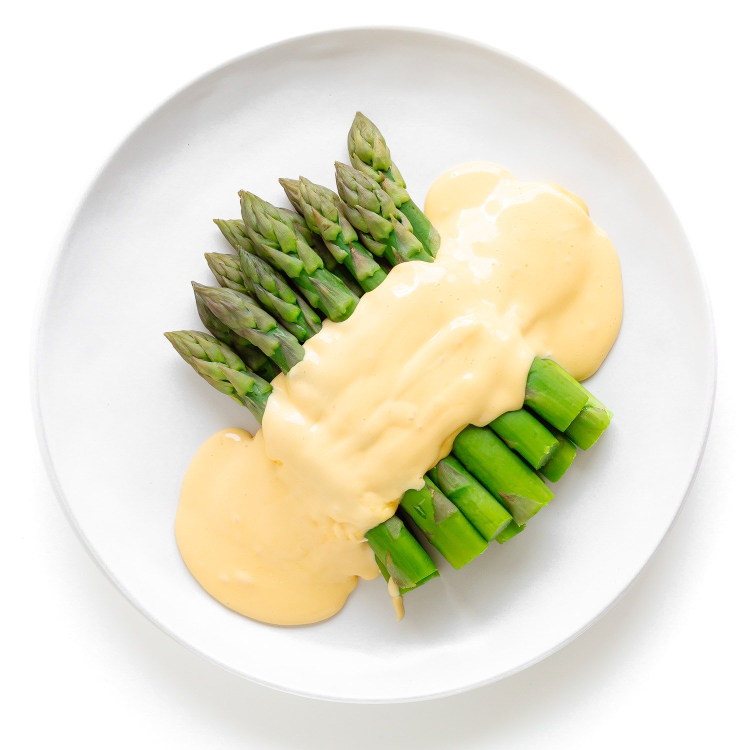 Steamed asparagus with hollandaise sauce on a white plate.