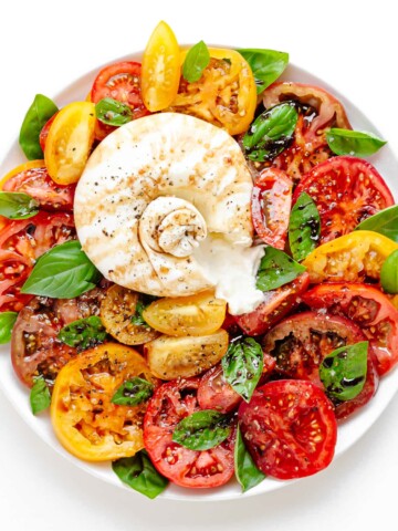 Burrata Caprese on a white serving plate.