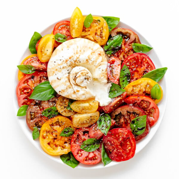 Burrata Caprese on a white serving plate.