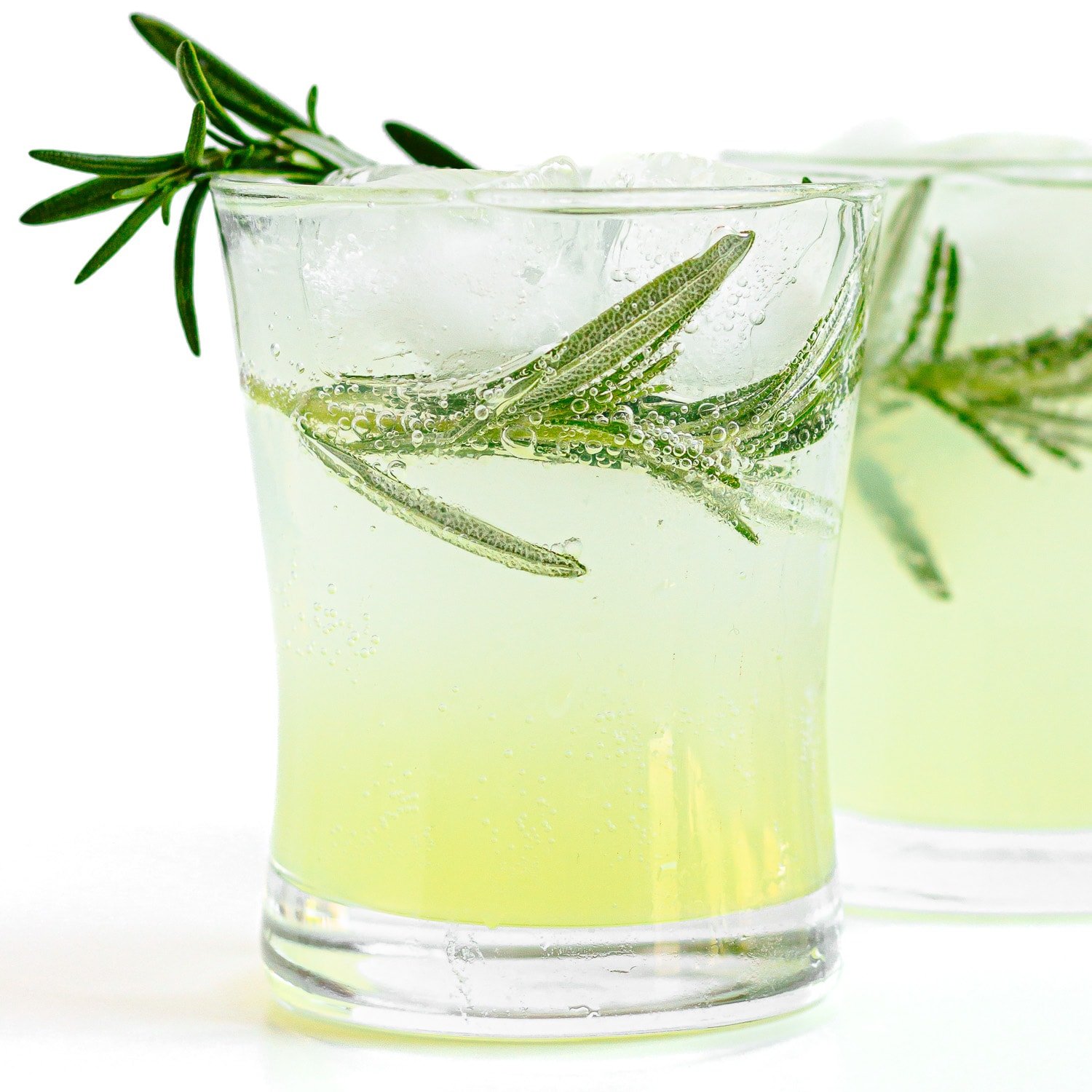 Two glasses of limoncello and tonic garnished with fresh rosemary.