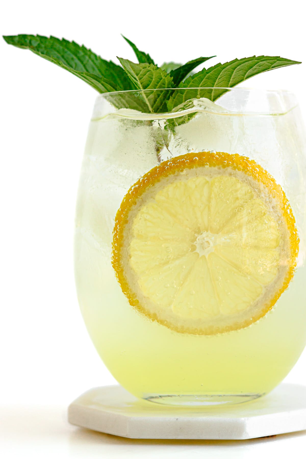 Closeup of a glass of limoncello spritz cocktail with a lemon slice and fresh mint.