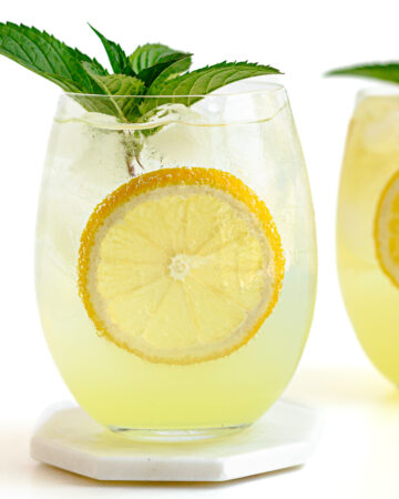 Two limoncello spritz cocktails garnished with lemon slices and fresh mint.