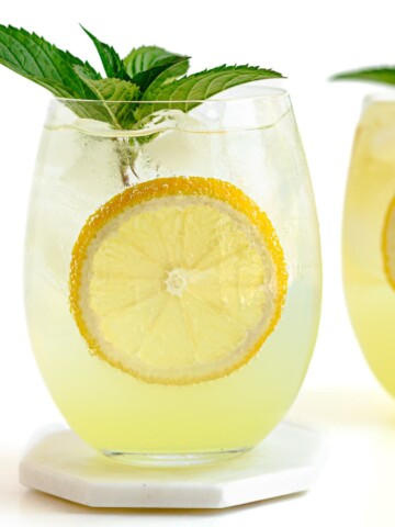 Two limoncello spritz cocktails garnished with lemon slices and fresh mint.