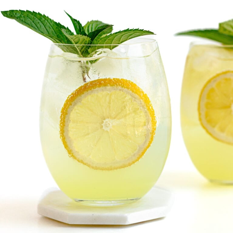 Two limoncello spritz cocktails garnished with lemon slices and fresh mint.