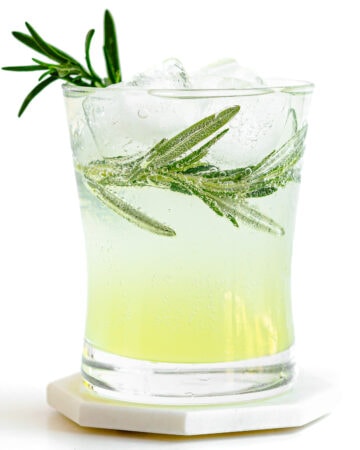 Glass of limoncello tonic garnished with fresh rosemary.