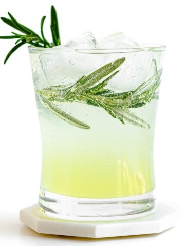 Glass of limoncello tonic garnished with fresh rosemary.