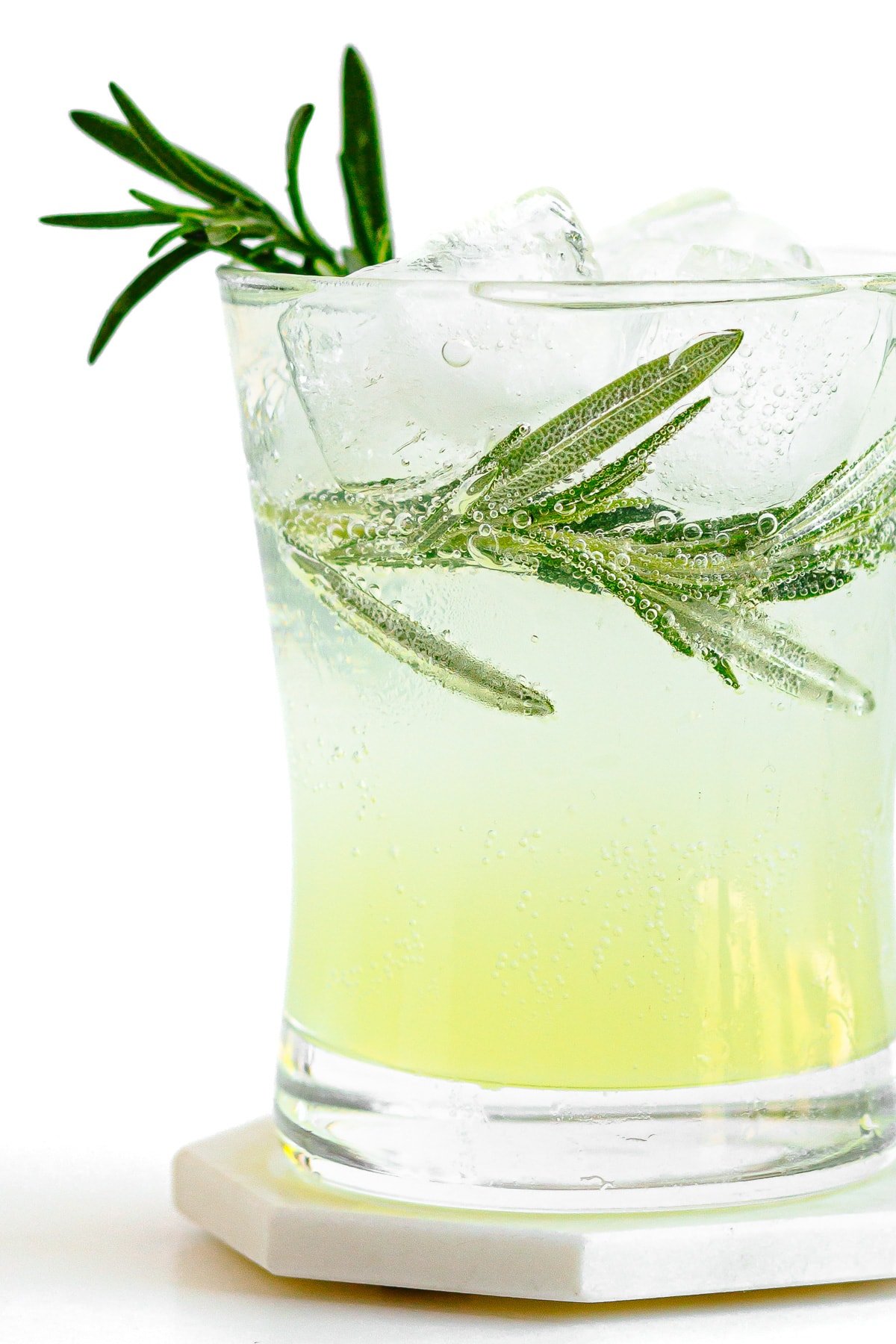 Close up of a glass of limoncello tonic garnished with rosemary.