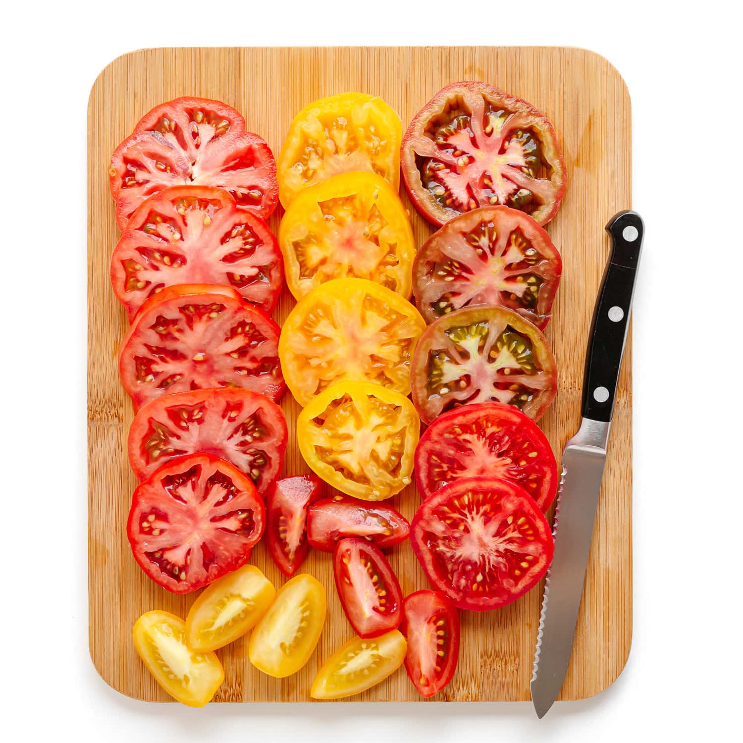 Sliced tomatoes on a wood cutting board.