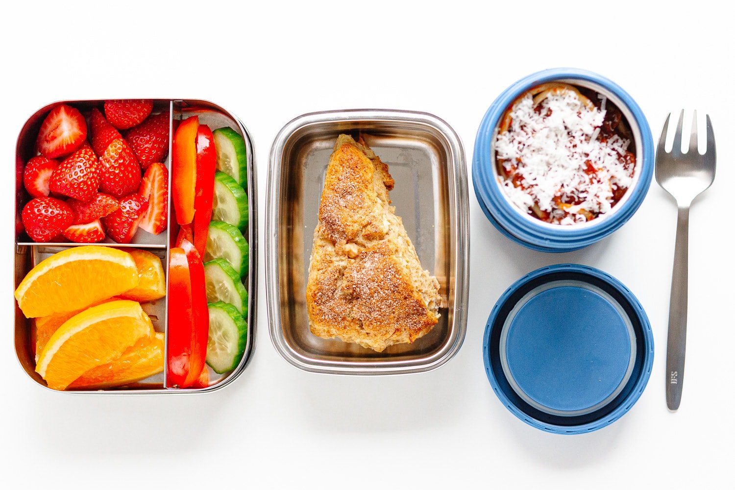 Packed school lunch containing a thermos with spaghetti bolognese, a container of mixed fruits and veggies and a container with an apple scone.