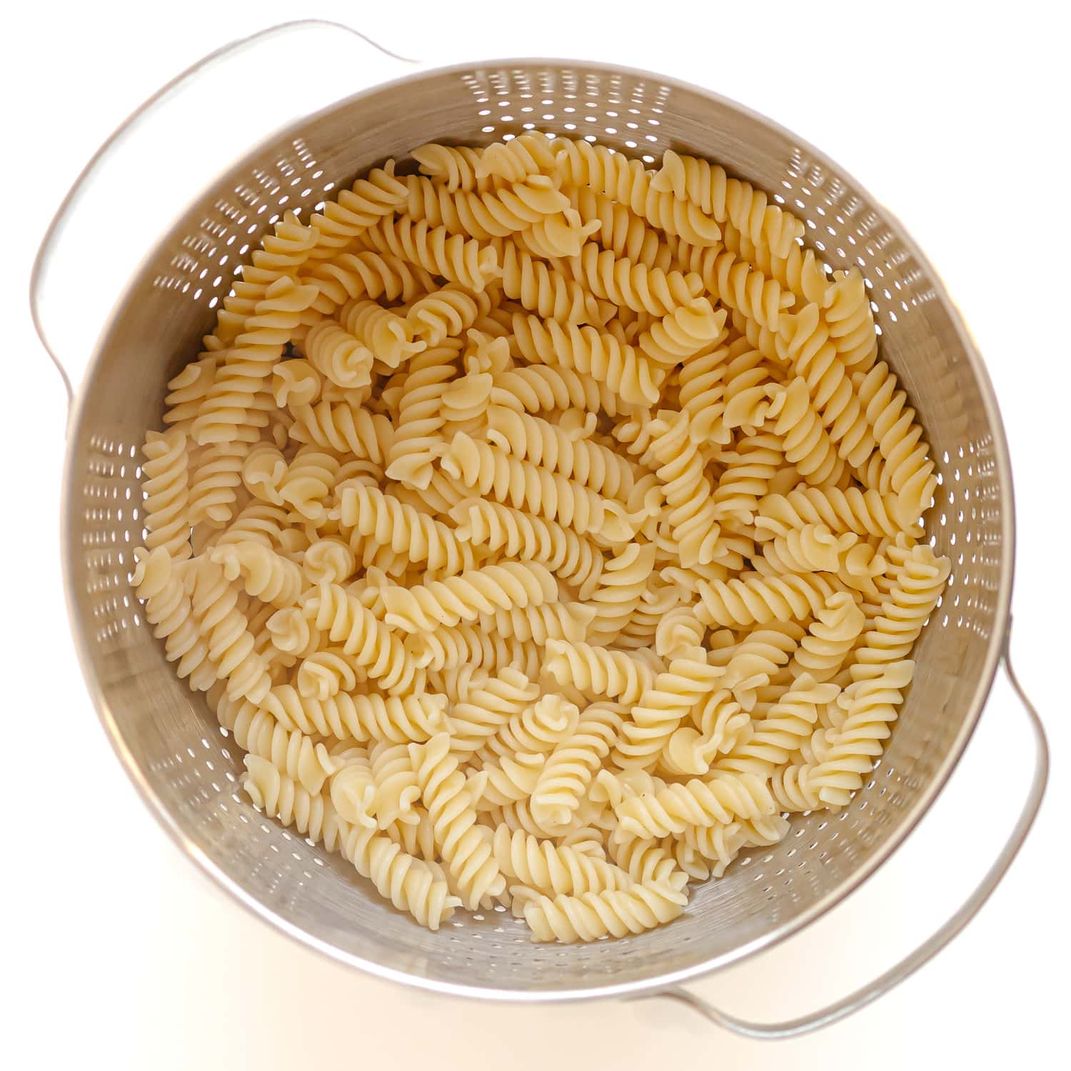 Cooked fusilli pasta in a stainless steel strainer.
