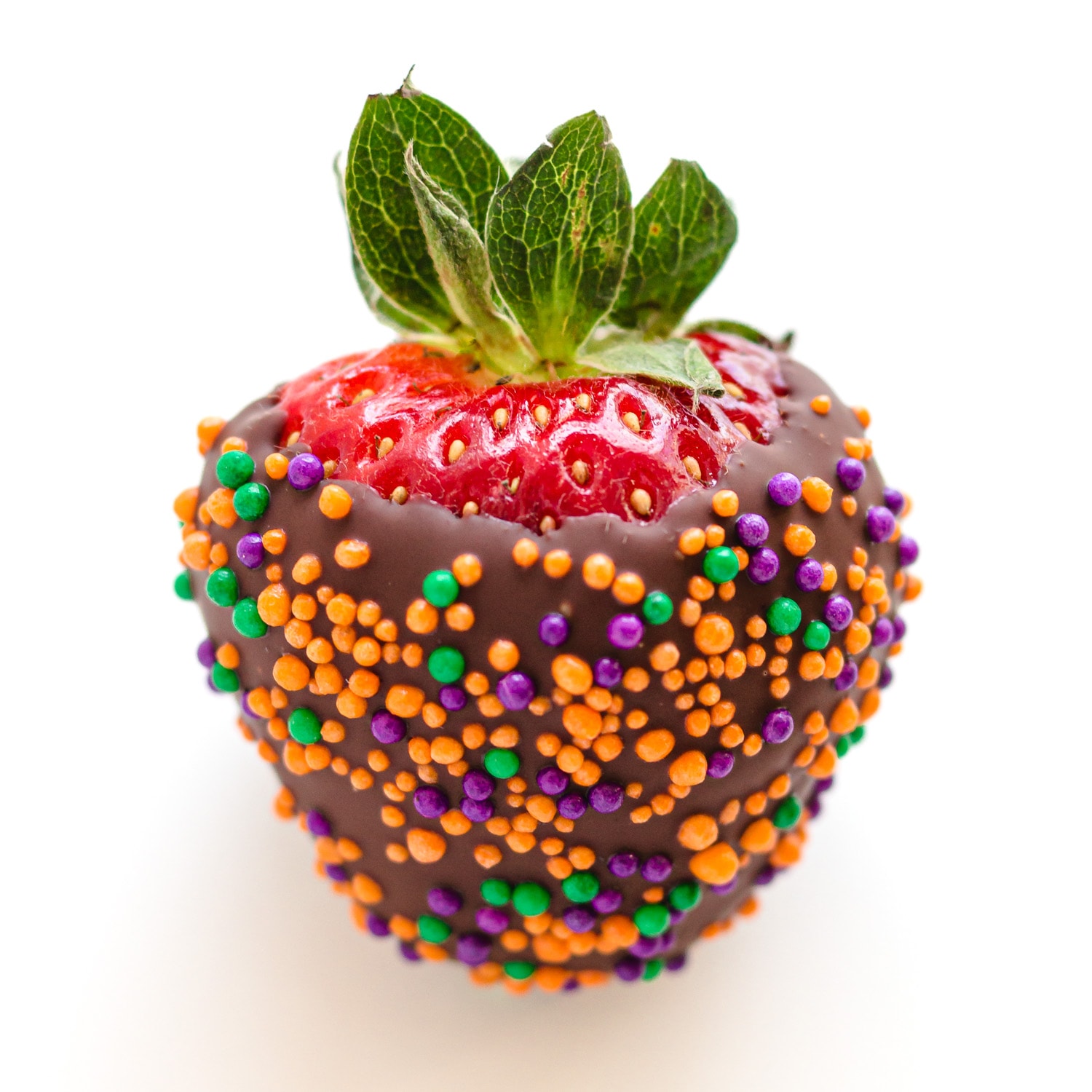 A chocolate covered strawberry covered in Halloween colored sprinkles.