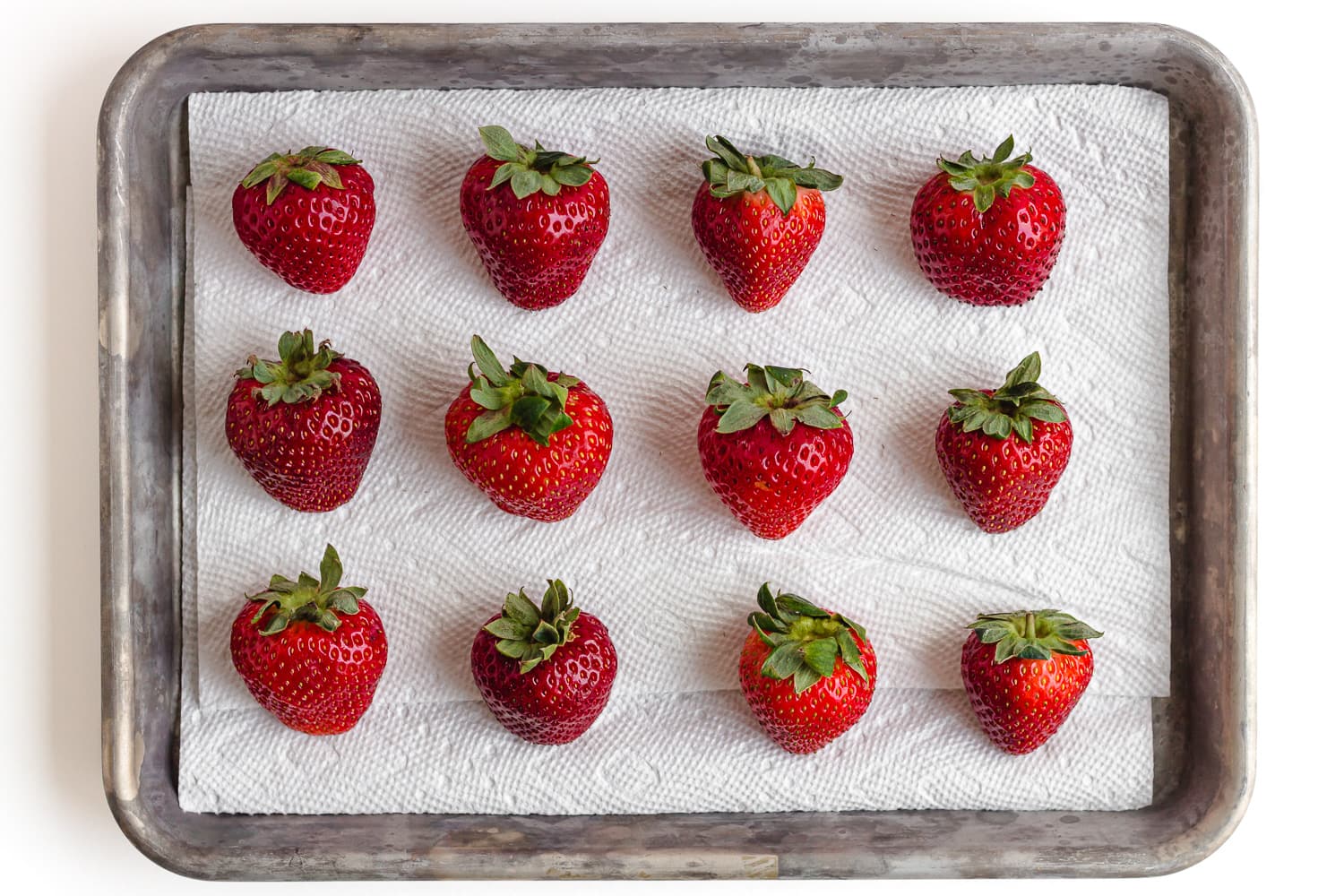 Washed and dried strawberries set out on a tray lined with paper towel.