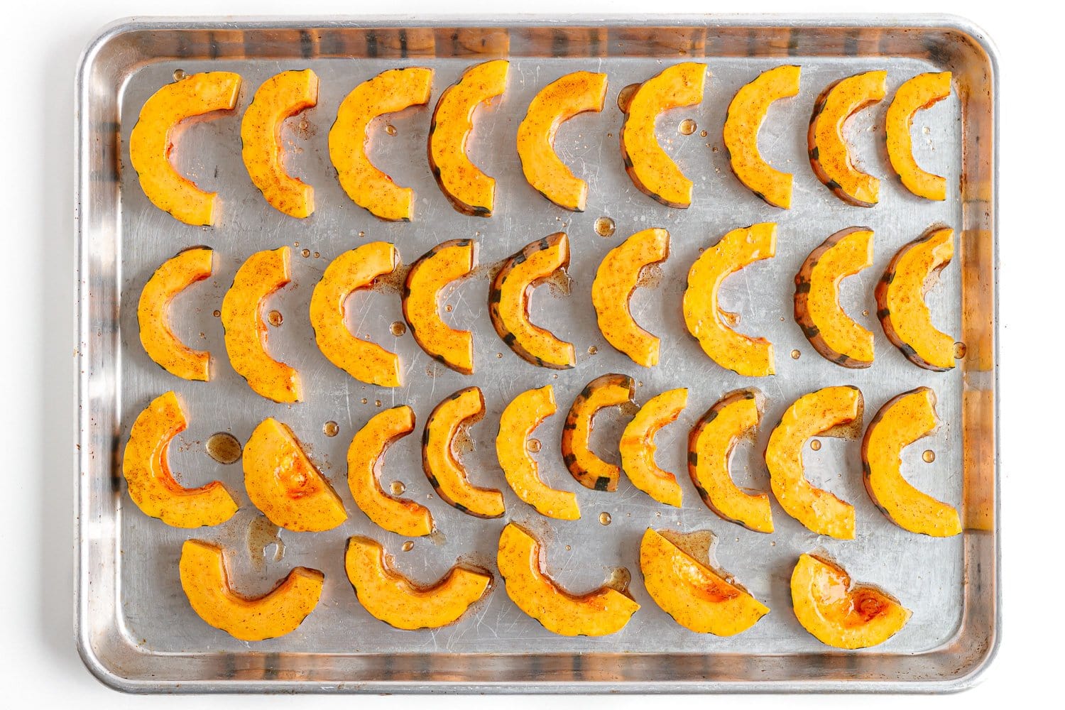 Delicata squash slices arranged on a baking sheet for roasting.